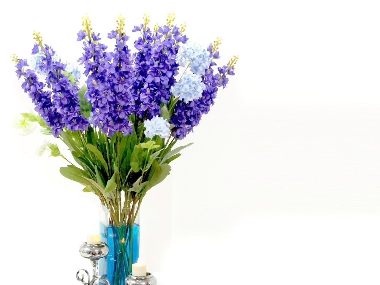 Bloeiende lentebloemen rond pastelkleurige kaarsen.