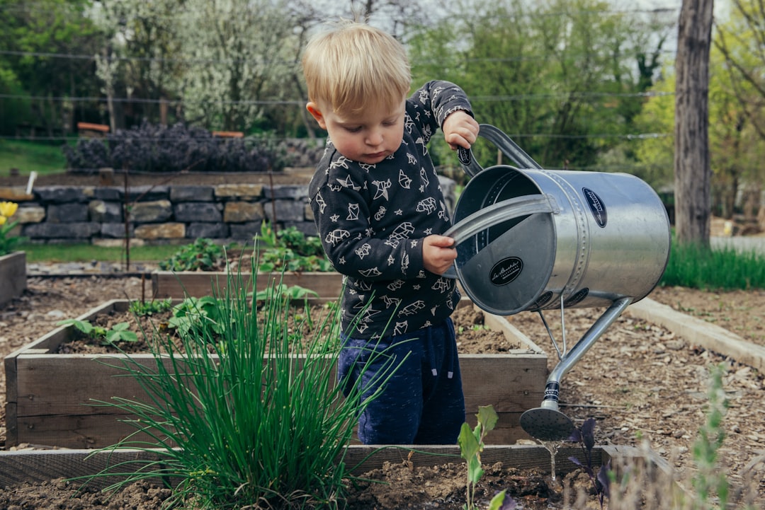 Kinderen planten bloemen in een zomerse tuin.